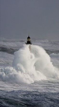 A lighthouse is in the middle of an ocean wave.